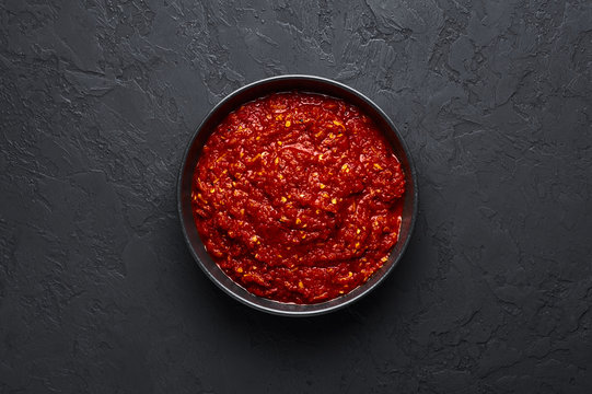 Schezwan Sauce in black bowl at dark background. Schezwan Sauce is Indo-chinese or Sichuan cuisine hot sauce with red chilli, garlic and ginger.