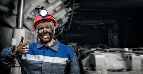 Portrait working young male miner in red cap showing thumbs up, excellent sign background coal...
