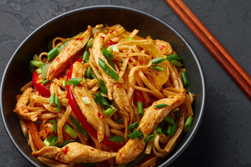 Chicken Schezwan Noodles or Hakka or Chow Mein in black bowl at dark background. Schezwan Noodles is indo-chinese cuisine hot dish with udon noodles, vegetables and chilli sauce or Schezwan sauce