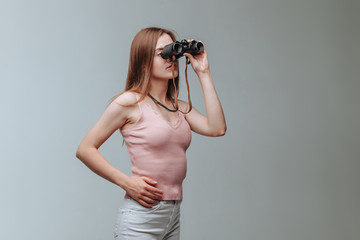 Girl looking through binoculars on a gray background