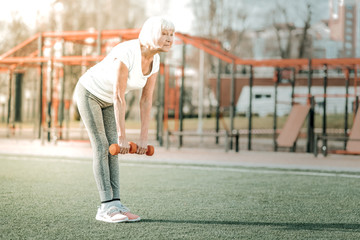 Obraz premium Nice strong senile mam practicing forward bends holding weights