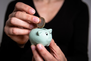 Savings and finance concept. Putting euro coin in small piggy bank, close-up.