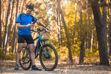 Fototapeta na wymiar Happy bearded man cyclist rides in the sunny forest on a mountain bike. Adventure travel.
