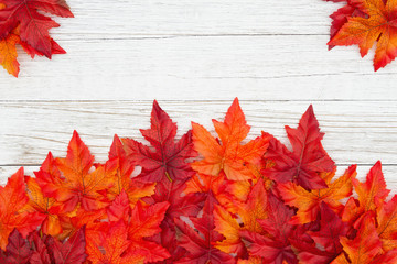 Red and orange fall leaves on weathered whitewash wood textured background