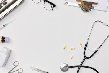 Creative flatlay of doctor medical equipment white table with stethoscope, medical documents,...