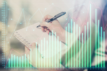 Multi exposure of hands making notes with forex chart huds. Stock market concept.