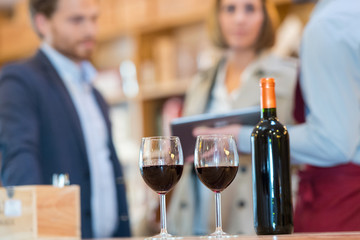 close up of glasses filled with red wine and bottle