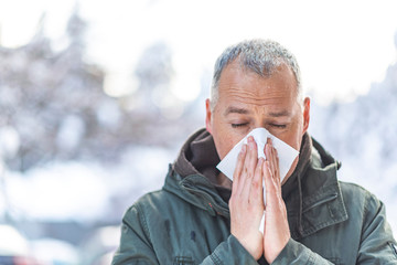 Sick mature man blowing his nose