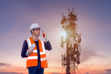 Asian engineer wearing safety helmet and safety glasses holding radio communication with man...