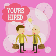 Conceptual hand writing showing You Re Hired. Concept meaning New Job Employed Newbie Enlisted Accepted Recruited Businessmen Colleagues with Brief Case Sharing Idea Solution