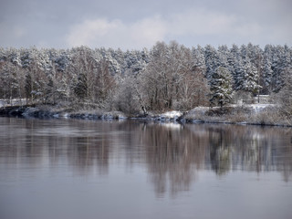 view of beautiful river winter day, snowy trees, many clouds, beautiful reflections, calm river water, Gauja river, Valmiera, Latvia