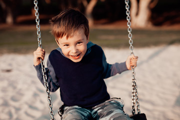 Child on swing, 5 year old boy, outdoors.