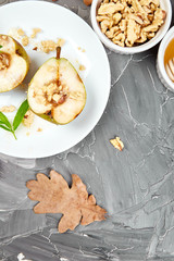 Tasty roast pears with honey and walnuts on white plates on grey background table. Top view.  Flat lay. Copy space.