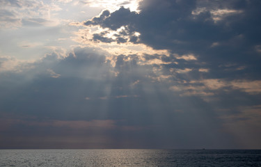 Naklejka na ściany i meble Summer rays of the sun pierce the clouds over the Black Sea