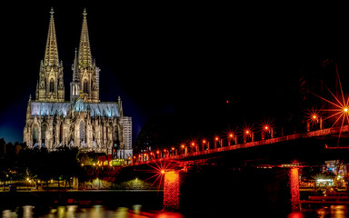 Fototapeta na wymiar Night View of Cologne Cathedral (Kolner Dom) and Rhine river under the Hohenzollern Bridge, Cologne city skyline at night, North Rhine Westphalia region, Germany.