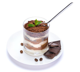 Classic tiramisu dessert in a glass cup on the plate and pieces of chocolate on white background with clipping path