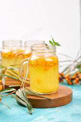 Colorful hot sea buckthorn tea with ginger and honey and sea buckthorn berries on blue table. Top view. Vitaminic healthy.