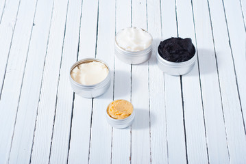 shea, macadamia nut and coffee butter, black cosmetic mud on white wooden table background