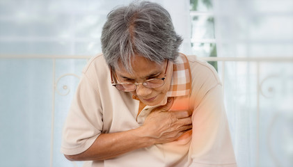 Asian old woman with chest pain suffering from heart attack at home