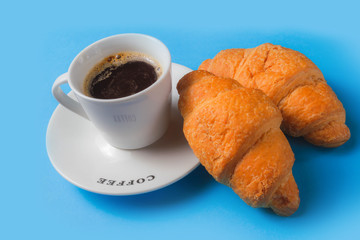 Croissant and espresso on a blue background. copy space