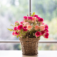 Flowers are in a wooden vase. Placed near the glass window on the wooden table in the room Giving a feeling of being in the spring.