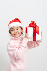 Girl holding a gift box in sweater and santa hat