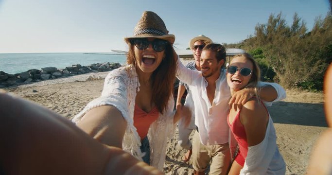Slow motion of group of young multi-ethnic friends are having fun to make a selfie or video call with a smartphone just arrived with minivan on a beach with a sea.