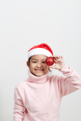 Girl holding a red christmas ball in sweater and santa hat