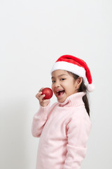Girl holding a red christmas ball in sweater and santa hat