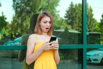 Surprised shocked young woman looking at phone