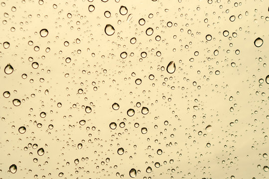Raindrops falling on the glass of the car. Suitable for use in abstract backgrounds.