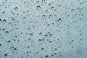 Raindrops falling on the glass of the car. Suitable for use in abstract backgrounds.