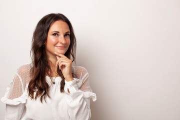 Junge Frau überlegt vor weißem Hintergrund mit Platz für Text oder Werbung