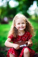 Beautiful smiling girl in a red dress holding a camera