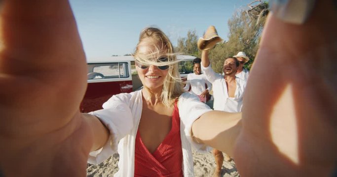 Slow motion of group of young multi-ethnic friends are having fun to make a selfie or video call with a smartphone just arrived with minivan on a beach with a sea.