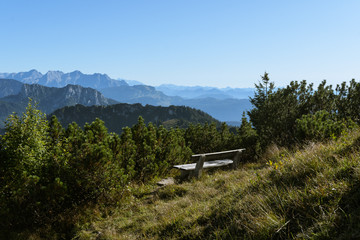 Leere Bank fvor Alpenpanorama bei Sonne und blauem Himmel im Herbst