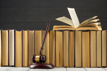 Legal Law concept - Open law book with a wooden judges gavel on table in a courtroom or law...
