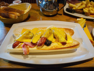 Traditional Irish breakfast served on a white plate, White bread roll, black pudding, sausages, cheese, fried egg and rushers. Selective focus.