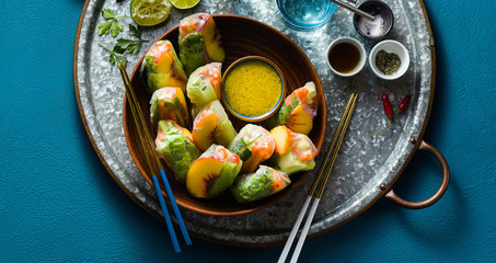 banner of vegan spring rolls of vegetables and peach with pistachio sauce on a tray. healthy food . shot from above. copy space