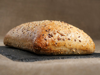 Fresh sourdough bread with nuts on a slate plate and hessian cloth.