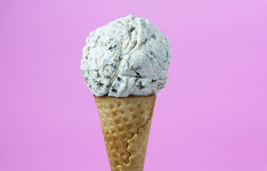 Cookies & Cream ice cream scoop in waffle cone on pink background, Closeup Front view Food concept..