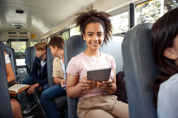 Classmates going to school by bus sitting girl close-up using app on digital tablet smiling joyful