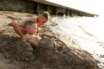 Kid burying his brother in sand