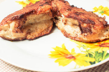 Cooked fried sea bass in plate on kitchen table.