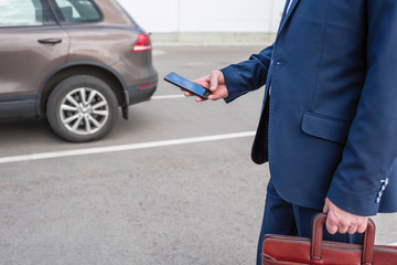 Customer hand holding mobile phone for opening car door. Car sharing service or rental concept.