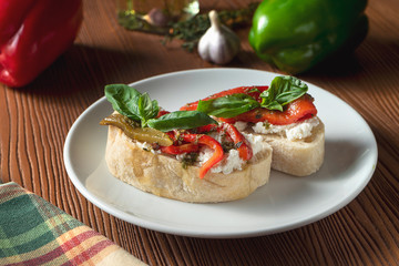 bruschetta with bell pepper, basil, pesto sauce and mozzarella on a white plate on a wooden background. Italian restaurant. Top view food photo