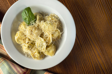 Fresh, homemade Ravioli with meat, decorated with parmesan and basil on a wooden background. CLose up, selective focus. Italian cuisine,food photo background. Top view