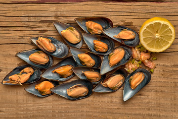 Mejillones al vapor abiertos sin la cascara de arriba con limón y picadillo de verdura sobre una...