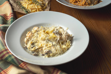 Close up view Pasta with wild mushrooms, white sauce, Parmesan cheese on wooden background. Food photo italian cuisine.