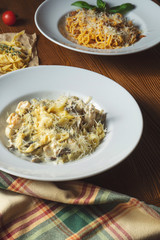 Close up view Pasta with wild mushrooms, white sauce, Parmesan cheese on wooden background. Food photo italian cuisine.